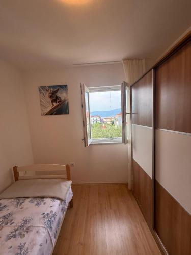 a small bedroom with a bed and a window at Apartman Pijuk in Slatine