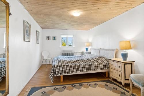 a bedroom with a bed and a table and a mirror at Rolsø Retreat - the apartment in Knebel