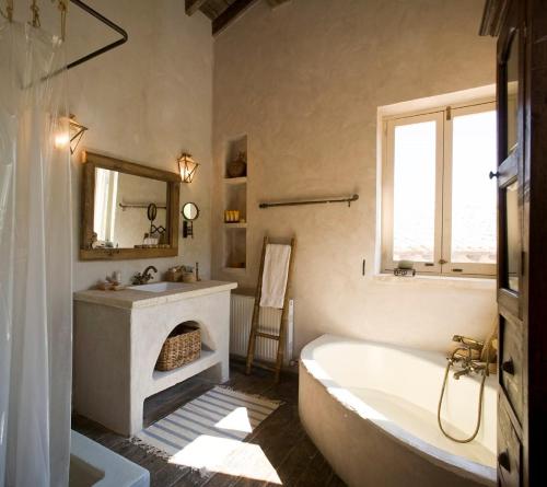 a bathroom with a tub and a sink and a mirror at Aphrodite's Oasis in Pomos