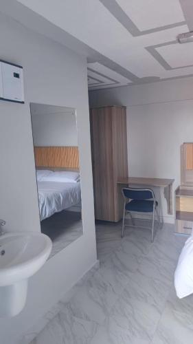 a bedroom with a bed and a sink and a desk at Rimayalounge in Embu