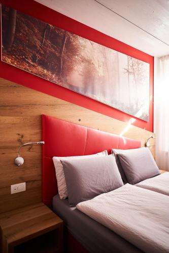 a bedroom with two beds with a red headboard at La Filanda Relax&Gourmet in Denno