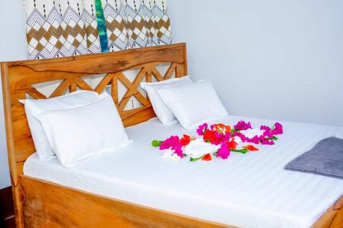 a bed with two pillows and flowers on it at Ecokayak Beach Lodge in Zanzibar City