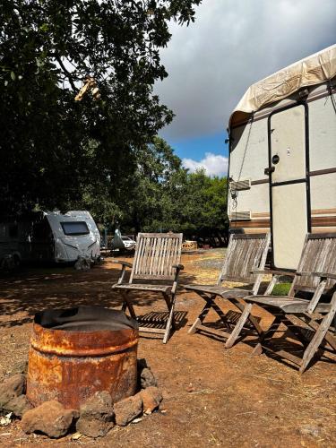 two chairs and a barrel in front of a rv at קרוואן עם חיוך in Odem