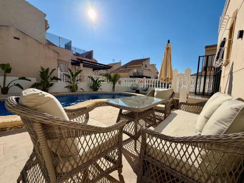 a patio with chairs and a table and a pool at Villa Emika with private pool in Ciudad Quesada in Ciudad Quesada