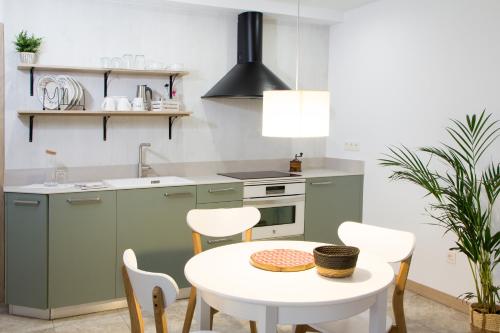 a kitchen with green cabinets and a white table and chairs at Tailer-Txiki in Apatamonasterio