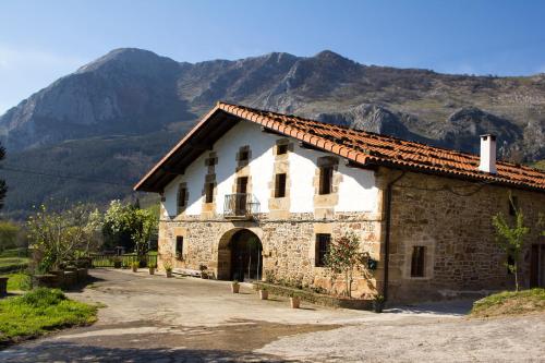 an old stone building with mountains in the background at Tailer-Txiki in Apatamonasterio