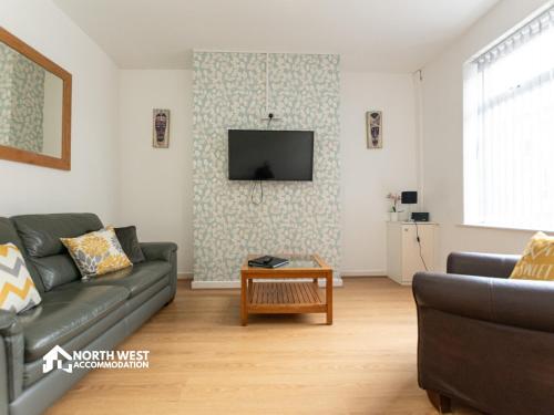 a living room with a couch and a tv on a wall at Leigh 2-Bedroom House Near Haydock & Wigan in Leigh