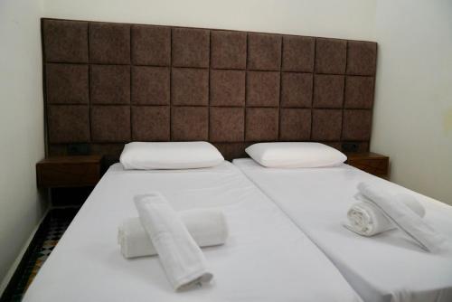 a bed with white sheets and towels on it at Riad Chouara in Fez