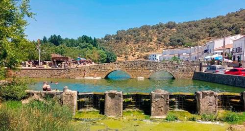 a bridge over a river with people in the water at Puerta de los Castañares A in Constantina