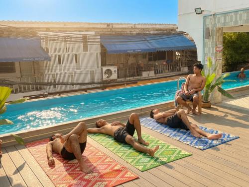 a group of people laying on mats by a swimming pool at Bangkok Group Bunk Hotel Khaosan in Bangkok