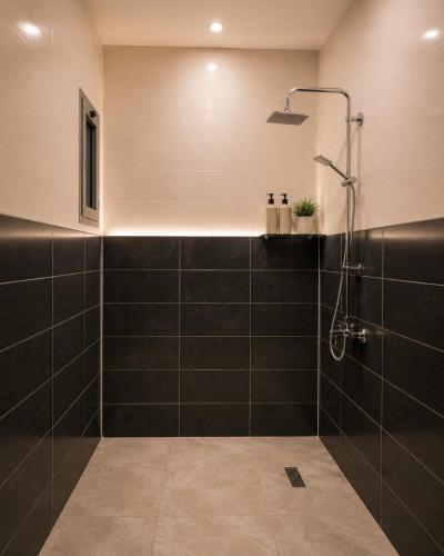 a bathroom with a shower with black tiles at StepInn in El Alamein