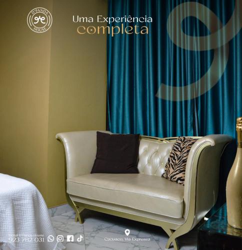 a couch sitting in a room with a blue curtain at Hotel DPanda House in Cacuaco