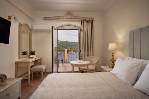 a bedroom with a bed and a desk and a balcony at Paleokastritsa Palace - Adults Only in Paleokastritsa