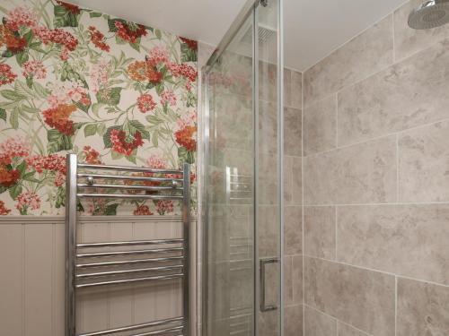 a shower stall in a bathroom with floral wallpaper at Lansdowne Grange in Bridlington