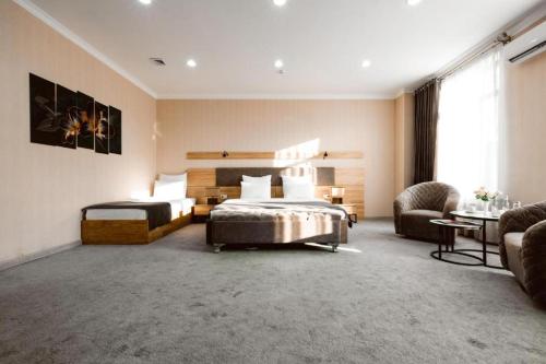 a bedroom with two beds and a couch and a chair at Valor Hotel in Tashkent