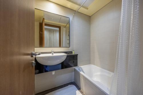 a bathroom with a sink and a tub and a mirror at Bloomfields 2BR+Maid in Mina Fajer - Fujairah in Fujairah