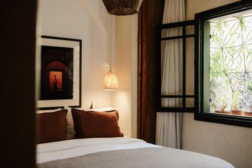 a bedroom with a bed with a mirror and a window at Riad Solange in Marrakesh