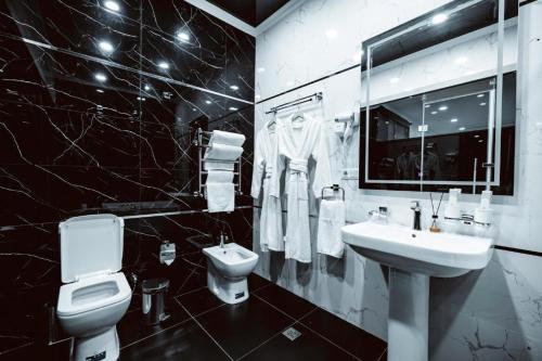 a black and white bathroom with a toilet and a sink at Valor Hotel in Tashkent