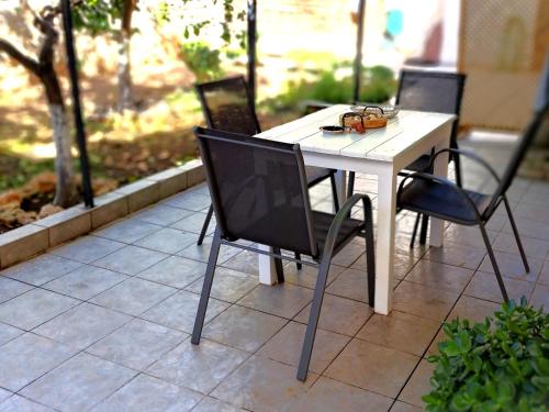 a white table with four chairs around it on a patio at Stone Family Home Garden Center Beach in Kyparissia