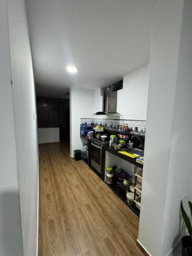 a kitchen with white walls and a wooden floor at Depa Ángel in Moyobamba