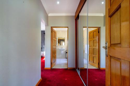 a hallway with a door and a red carpet at Alimama Spaces: Manson Mansion in Randjesfontein