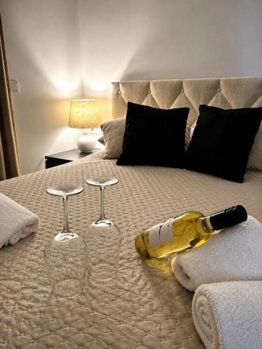 a wine bottle and two wine glasses on a bed at Sunset Aura in Sukošan