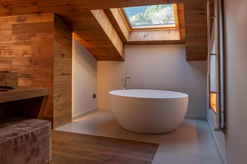 a bathroom with a large white tub in a room with wooden ceilings at Silou Retreat in Champdepraz