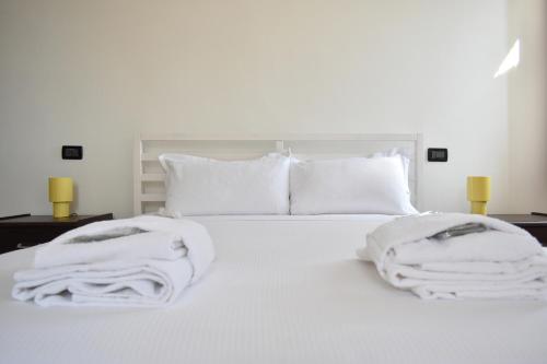 a white bed with white pillows and towels on it at Welc-ōM Conselve Matteotti in Conselve