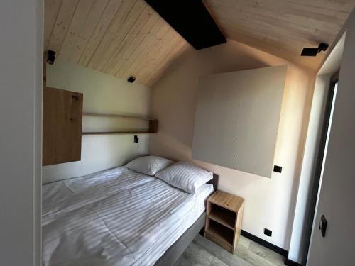 a small bedroom with a bed and a wooden ceiling at Marina Górkło - Żurawi Kąt in Górkło
