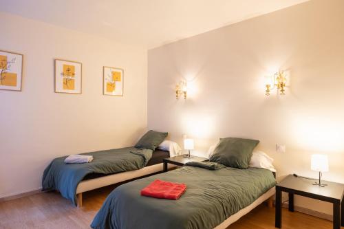 two beds in a room with two lamps on the wall at Gîte Le Scaphandre in Espalion