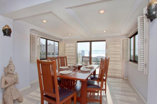 a dining room with a table and chairs and windows at Argyle Apartments Pattaya in Pattaya South