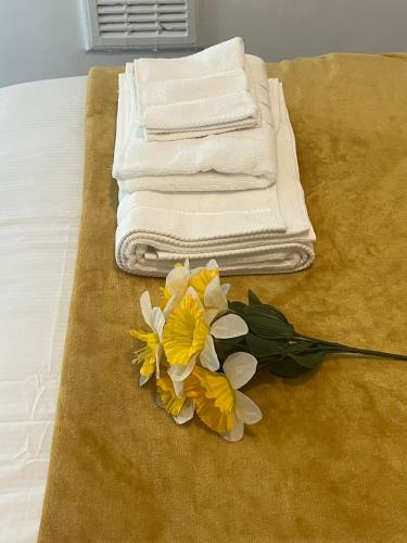 a pile of towels and a bouquet of flowers on a bed at Scorpio 1 in Burton upon Trent
