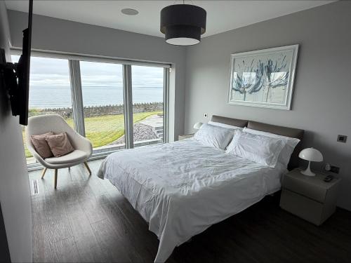 a bedroom with a bed and a chair and a large window at Slate House in Ballybunion