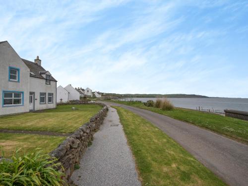 a road next to a house and a body of water at Jura in Drummore