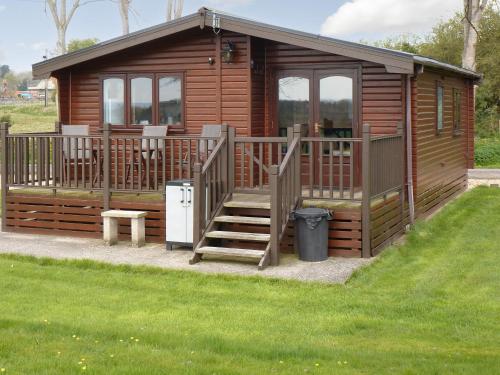 a large wooden cabin with a staircase and a porch at Wren Lodge - E5023 in Nawton
