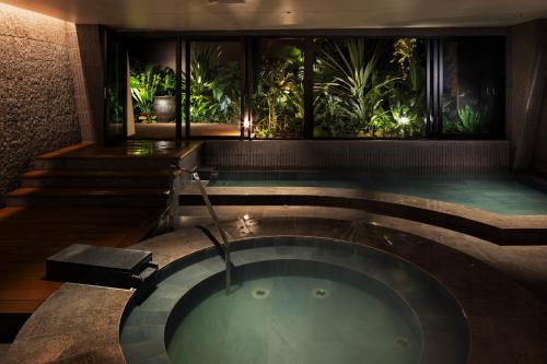 a jacuzzi tub in a bathroom with plants at South Gate Hotel Okinawa Naha Tomari Port - Direct Access to Tomarin in Naha