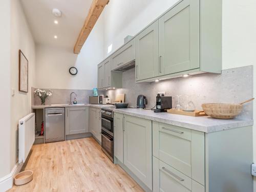 a kitchen with white cabinets and a wooden floor at The Old Stable in Dursley