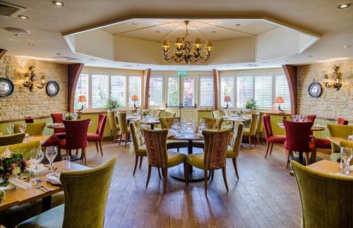 a restaurant with tables and chairs and a chandelier at The Crown Inn in Peterborough