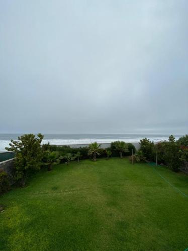 a lawn with the ocean in the background at Casa Catalina - Oceanfront house Lima in Lima