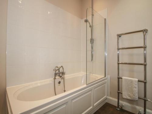 a white bathroom with a tub and a shower at The Butlers Quarters in Much Wenlock