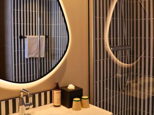 a bathroom with a sink with a mirror and a shower at Mercure Nice Promenade Des Anglais in Nice