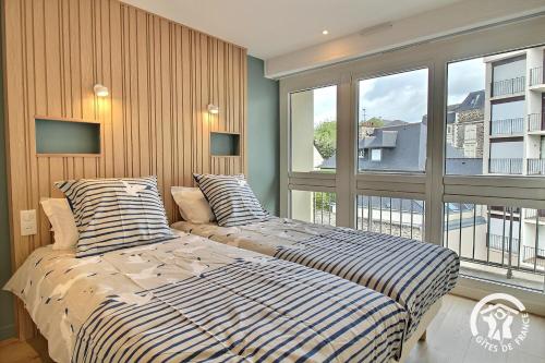 two beds in a bedroom with a large window at Ker helios in Dinard