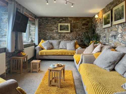 a living room with two couches and a stone wall at Mum's Cottage - Uk52136 in Henwood