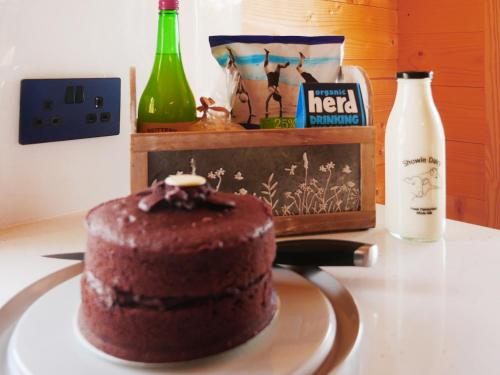 a chocolate cake on a table with a bottle of alcohol at Stable Lodge At Greenacre in Bromyard