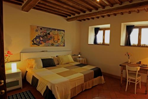a bedroom with a bed and a table and windows at Le Rogheta in Campiglia dʼOrcia