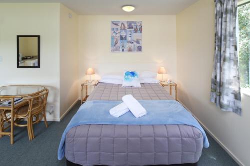 a bedroom with a bed with two towels on it at Waiheke Island Motel in Ostend