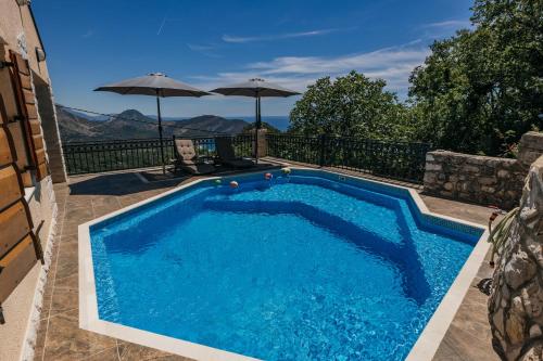 a swimming pool with blue water and two umbrellas at Villa Robinson in Petrovac na Moru
