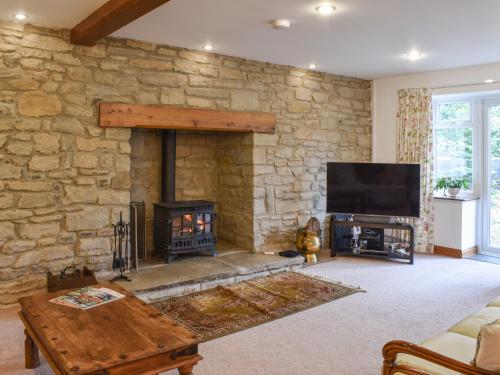 a living room with a stone wall with a fireplace at Wren Cottage in Lydney
