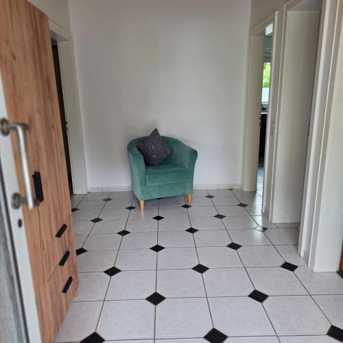 a room with a green chair and a tiled floor at Ferienhaus Schwerte Ergste im Ruhrtal in Schwerte