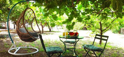 a swing and two chairs and a table under a tree at Garden house escape in Amarynthos